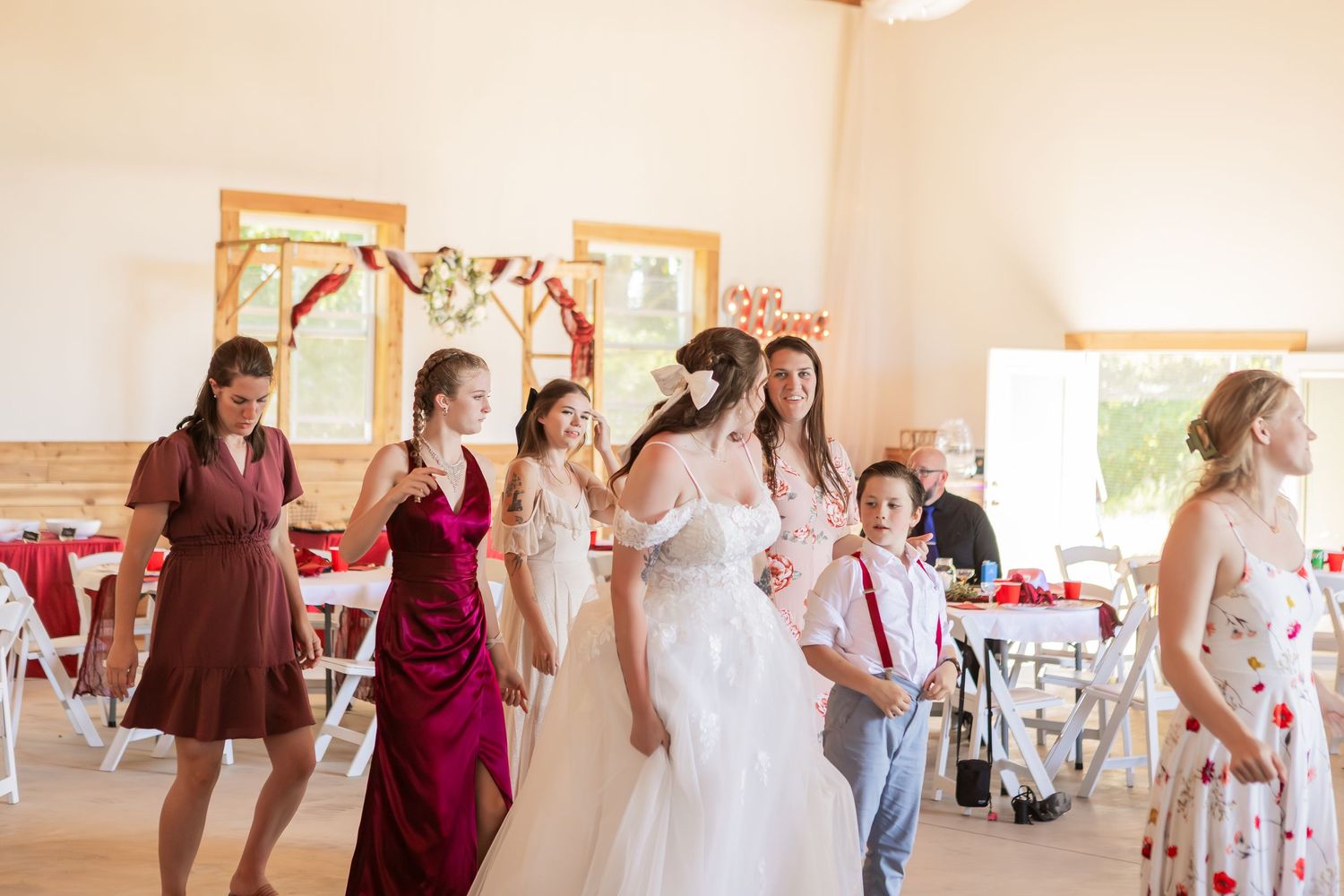 Wedding preparation scene with burgundy and white color scheme in bright indoor setting.