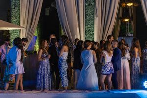Elegant guests mingling at an outdoor evening wedding reception with draped curtains and blue lighting.