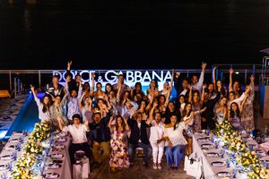 Large group celebrating at a Dolce & Gabbana branded outdoor dinner event at night with festive decorations.