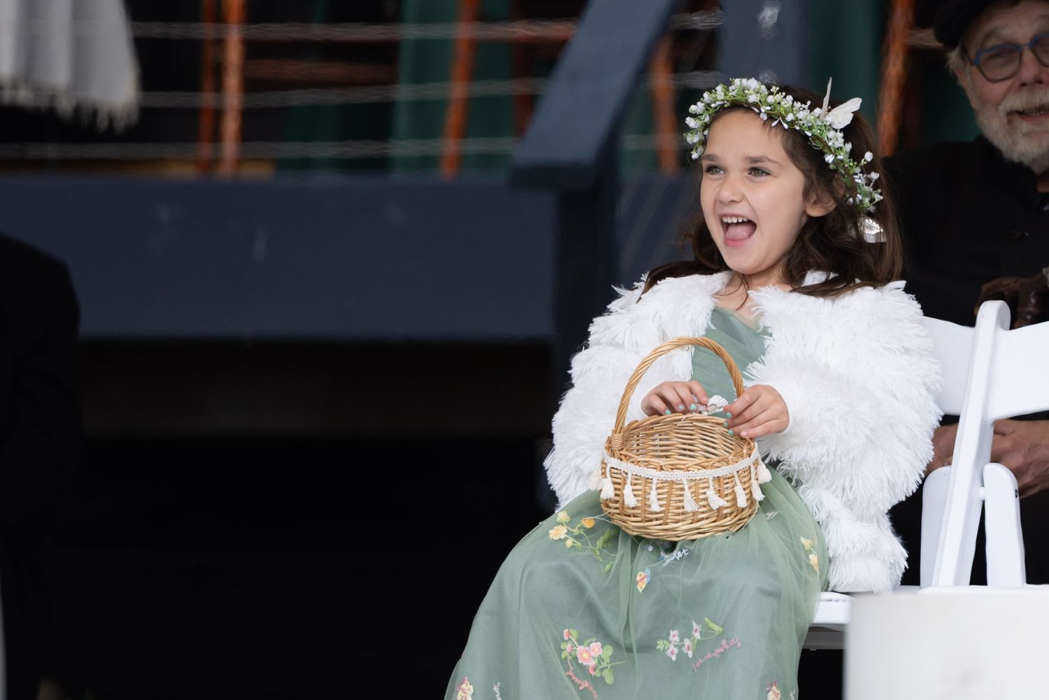 A young dancer in a mint green dress and floral crown performs expressively on stage during a recital.