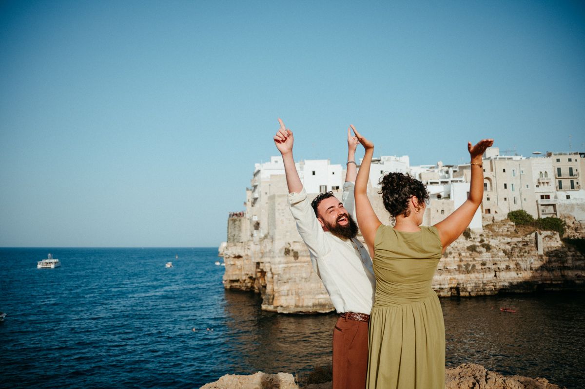 People enjoying a summer day on the rocky Mediterranean coastline with white cliffs and blue water in the background.