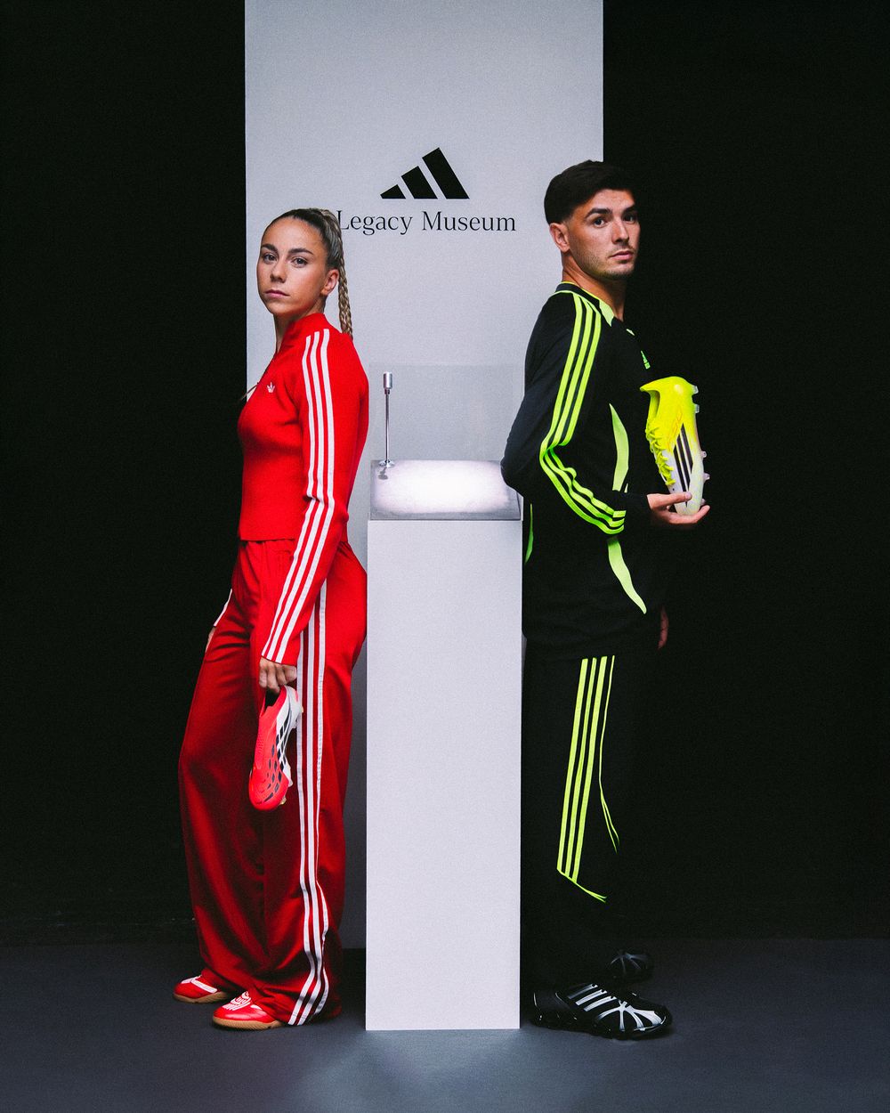 Models pose in contrasting red and neon yellow Adidas tracksuits against a stark black and white backdrop.