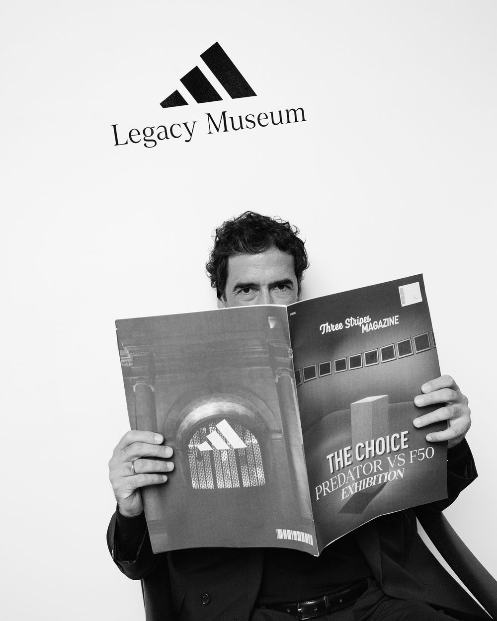 Black and white image showing multiple Adidas brand promotional materials and marketing books in a museum display.