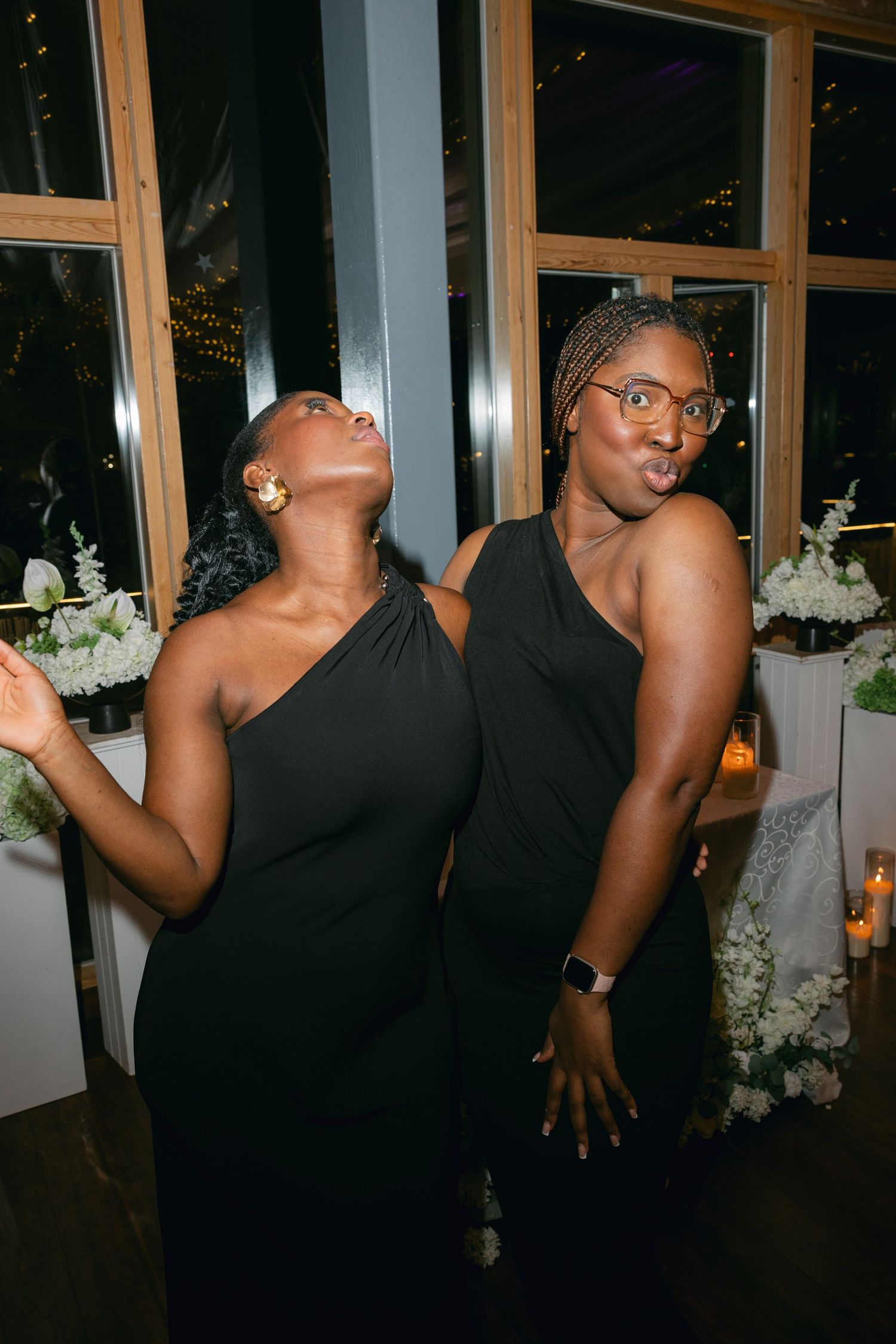 Wedding guests dancing and having fun at an evening reception with window views.