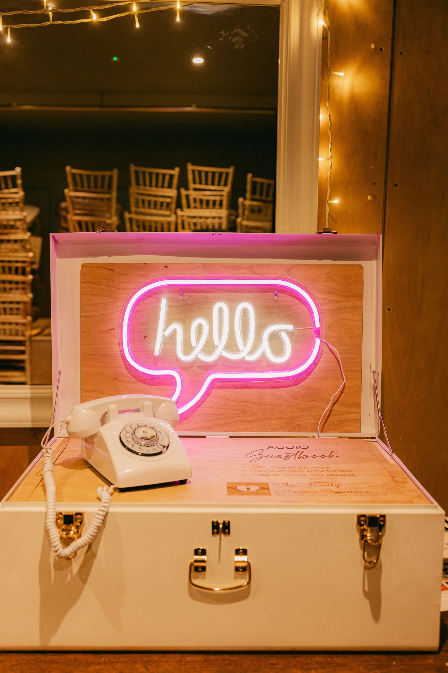 Pink neon hello sign displayed in white box against warm ambient lighting at an event venue.