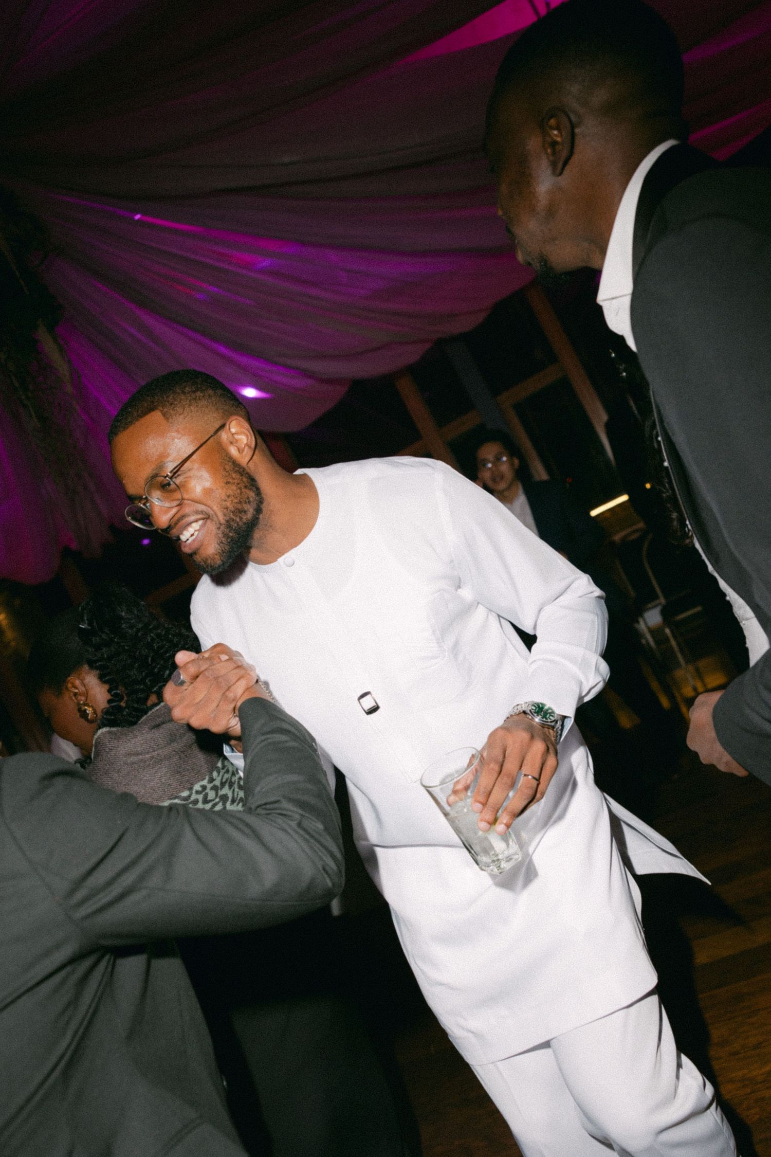 People dancing and enjoying themselves at a nightclub with purple lighting and a white tent-like ceiling structure.
