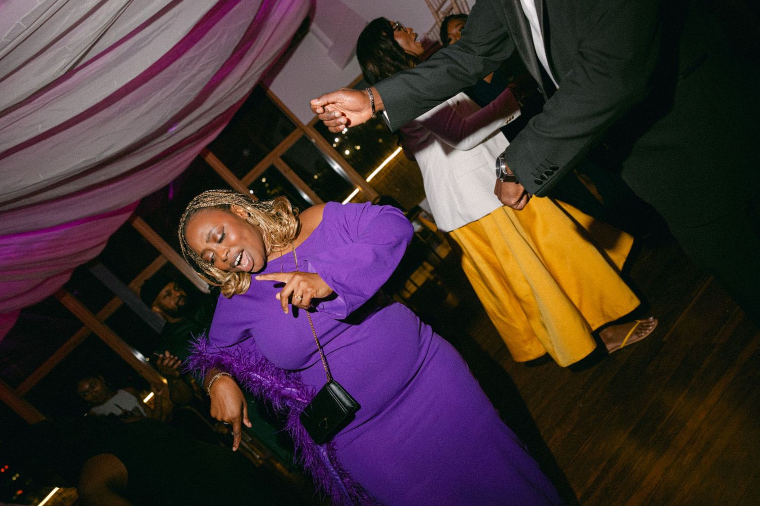 Wedding guests dancing and enjoying themselves under purple lighting.
