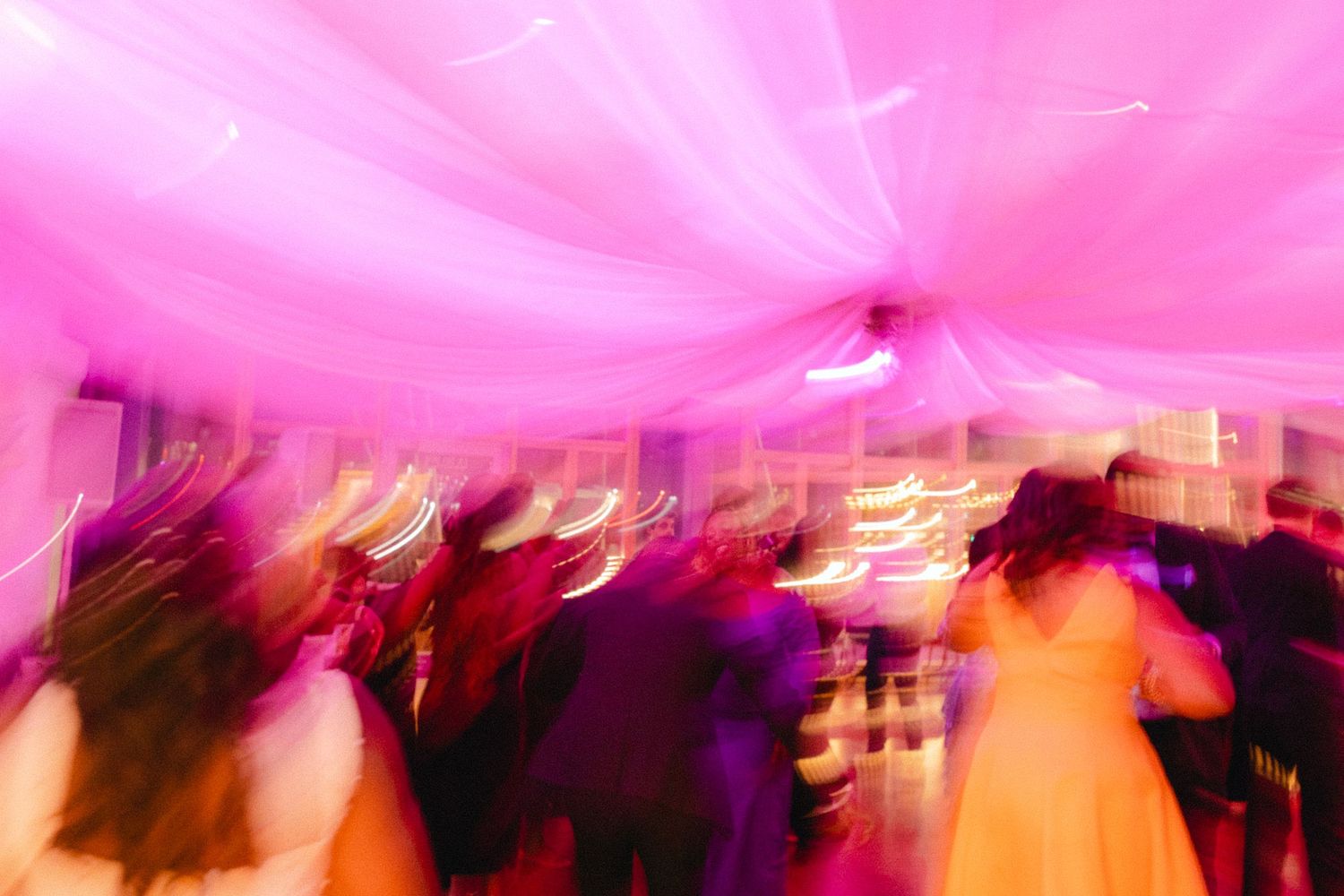Pink and orange blurred lights create an abstract pattern at what appears to be a nightclub or party venue.