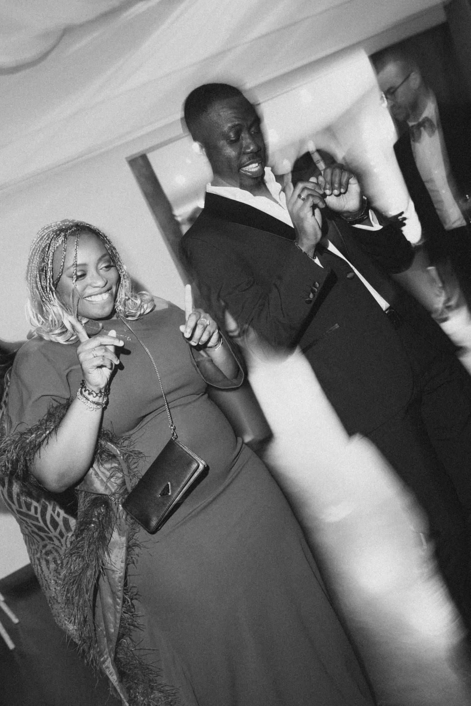 Black and white photo of guests dancing and celebrating at a wedding reception.