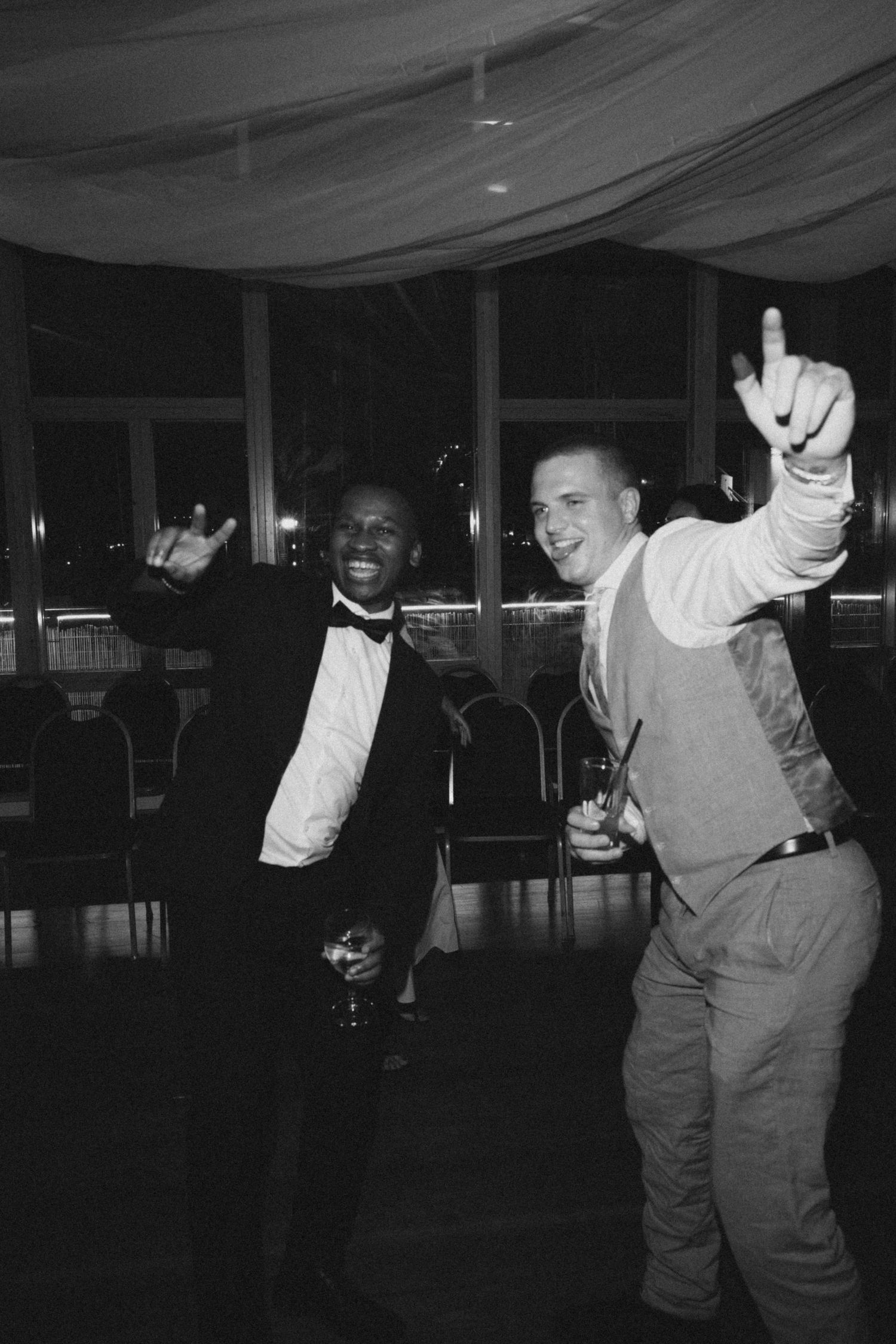 Two people dancing and having fun at a formal event, one in a bow tie and one in casual attire.