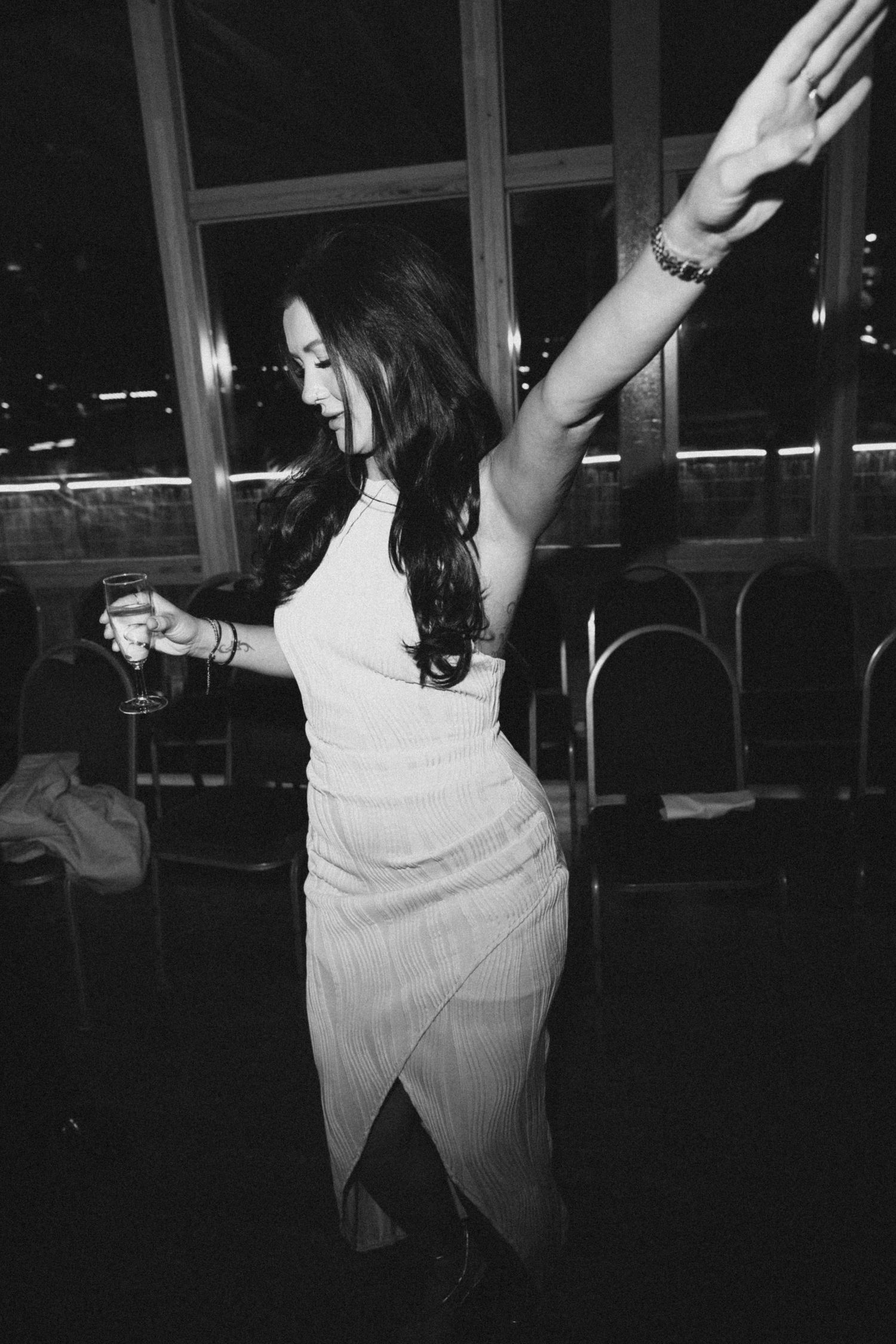 Black and white sequence of a person dancing expressively in a dark room with windows visible in the background.