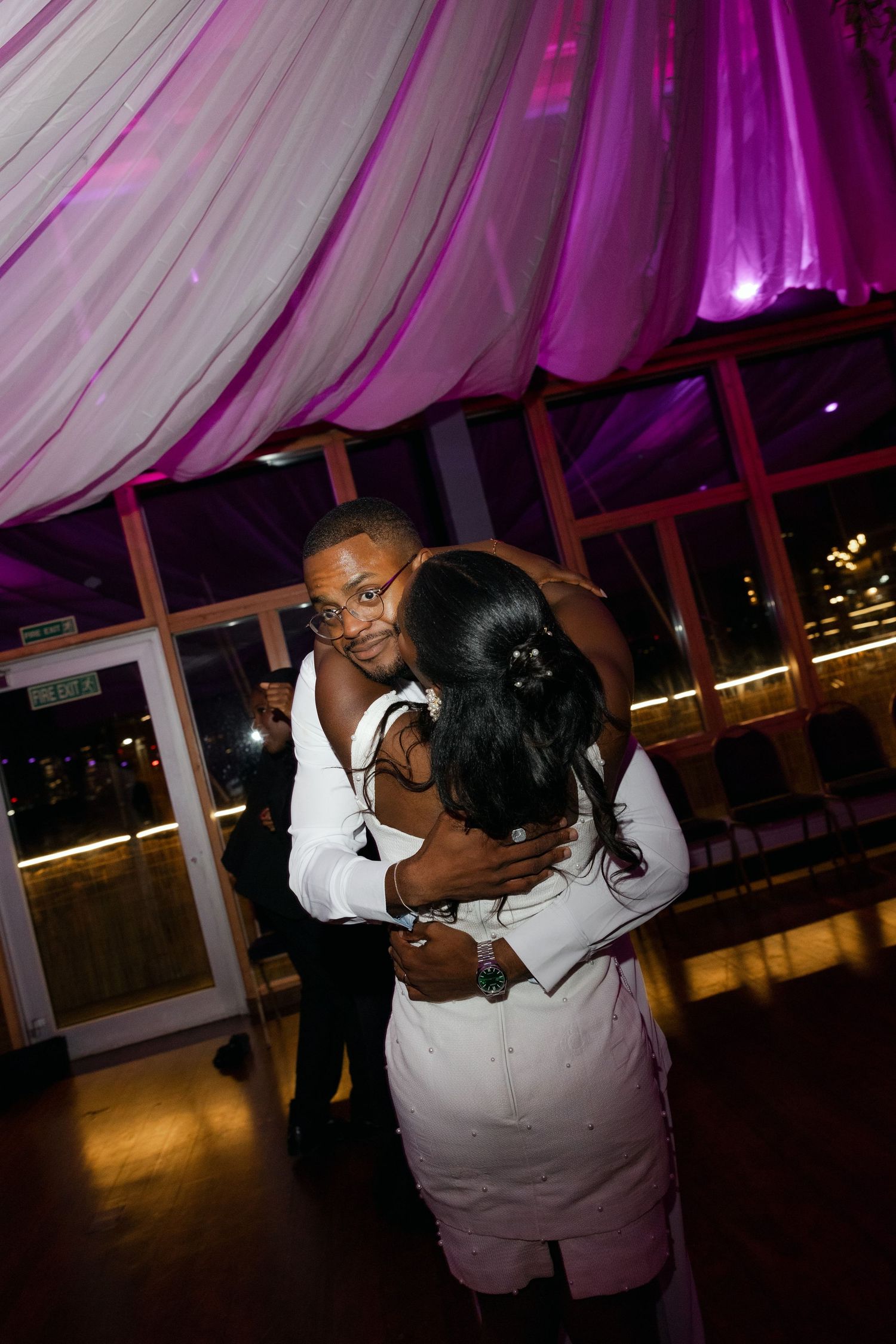 Guests slow dancing under purple mood lighting at an elegant evening event.