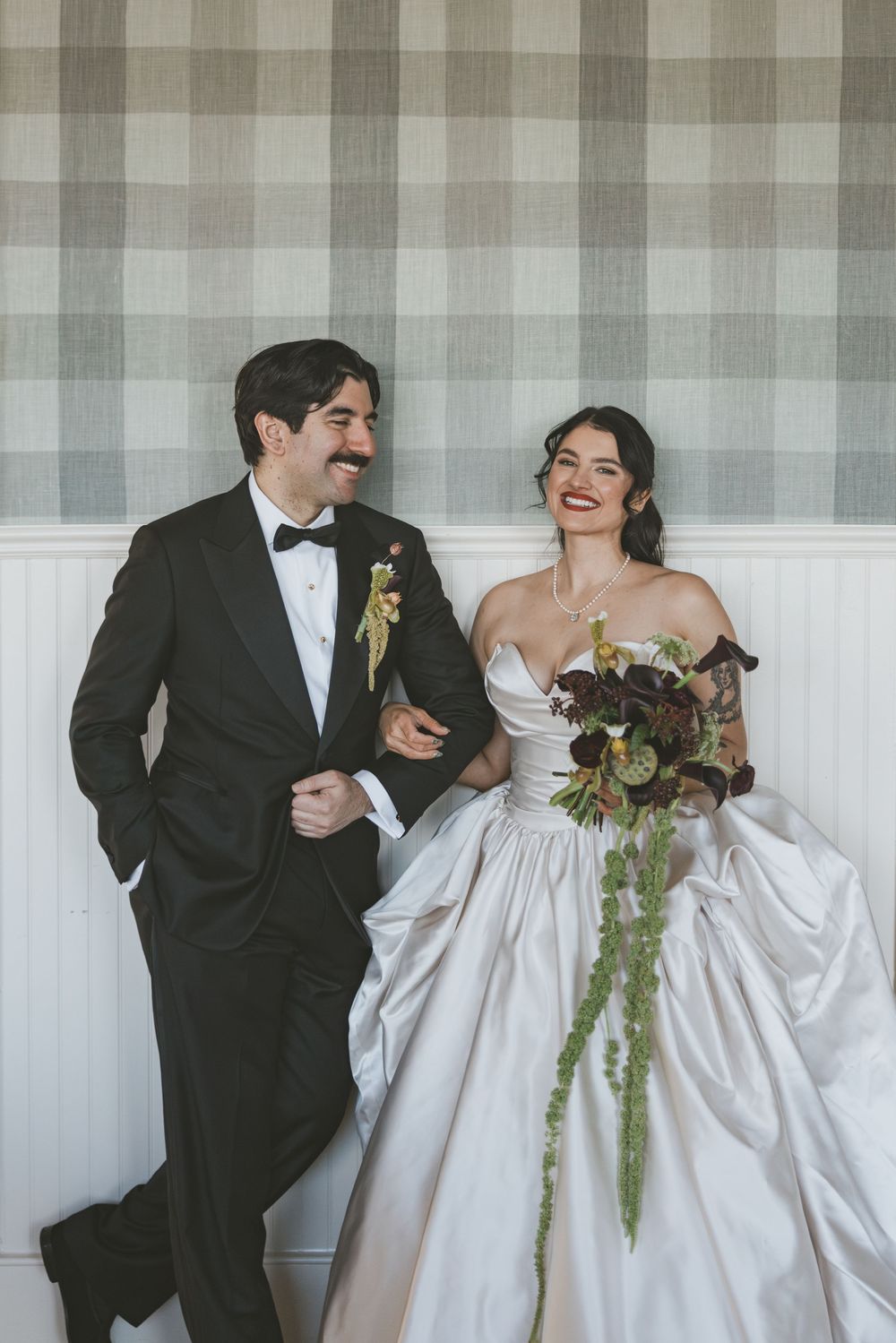 A candid wedding scene with the couple sharing laughter against a striped curtain backdrop.