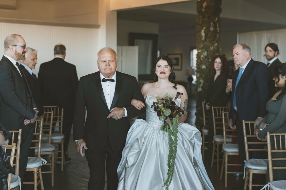 Guests mingle during a wedding reception in an elegant indoor venue with chiavari chairs.