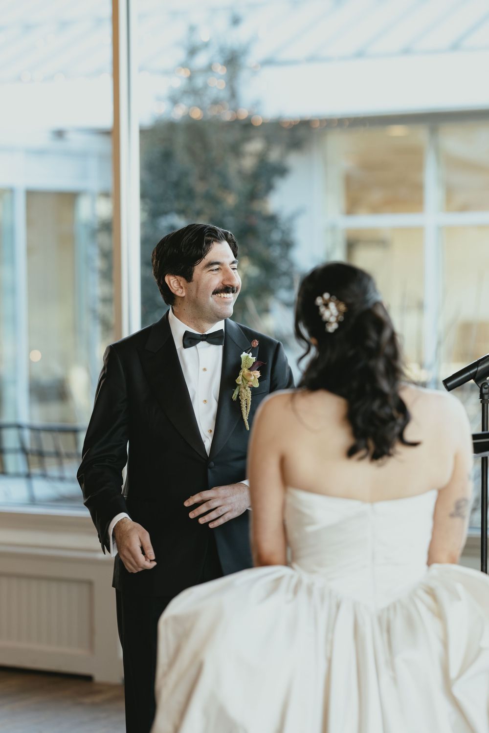 A couple shares a joyful moment during their wedding ceremony in a bright indoor venue.