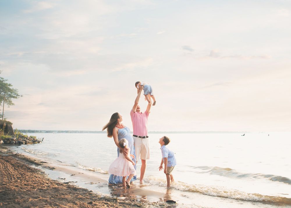 Family enjoying a playful moment together on a serene beach at sunset.