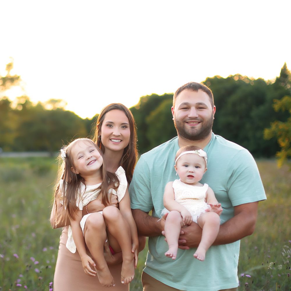 Casual outdoor family photography session in a summer meadow at golden hour.