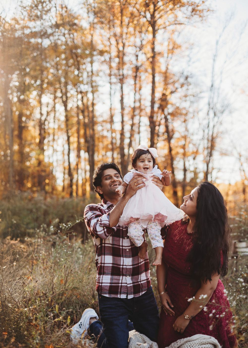 Family enjoying autumn moment together in forest setting with golden leaves.