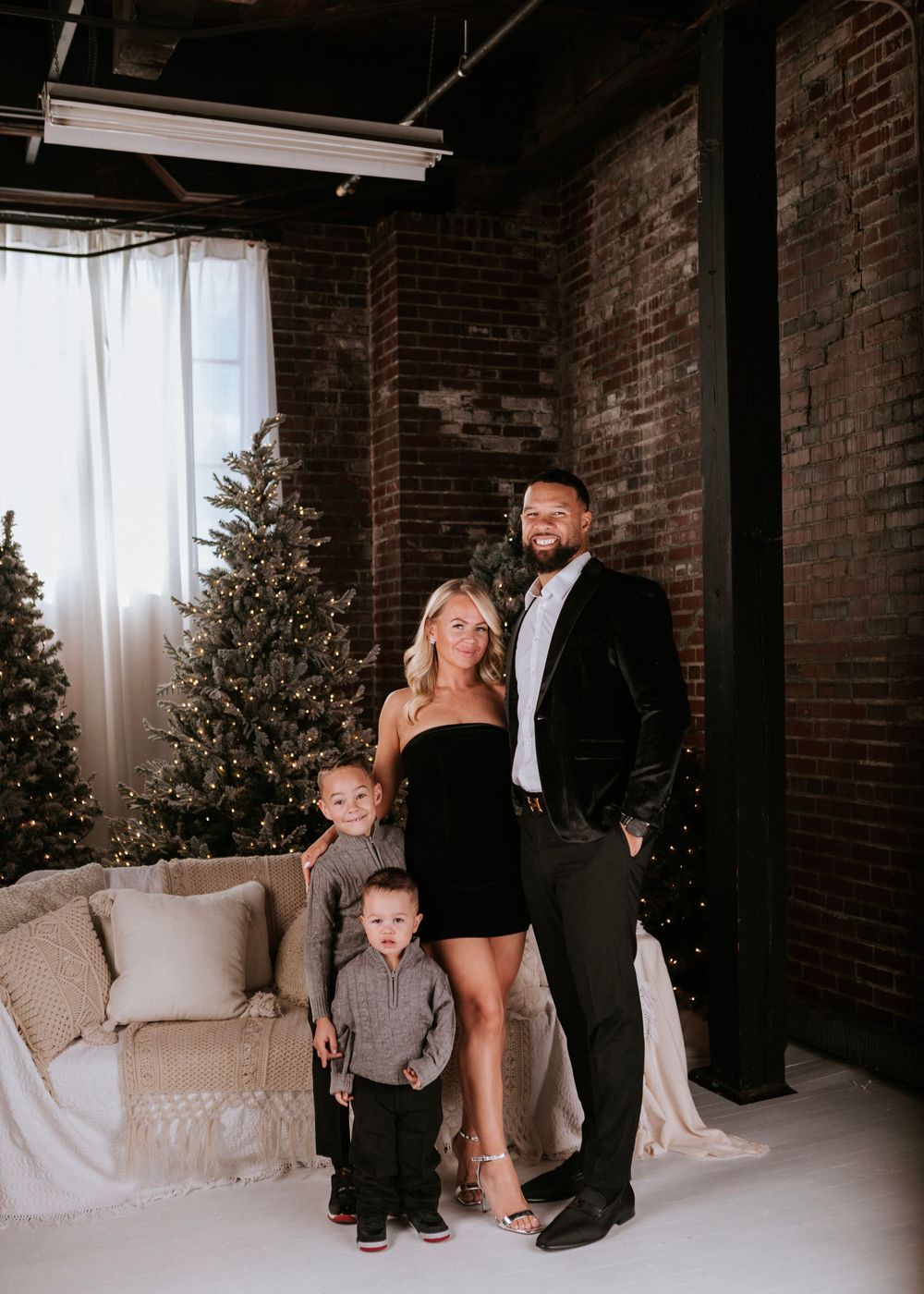 Elegant family portraits in a modern industrial space with brick walls and Christmas decor.