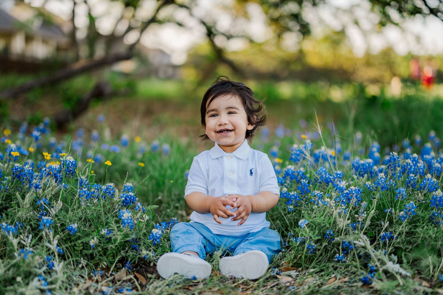 Child sitting in blooming bluebonnets during a Central Texas spring mini session with natural light photography.