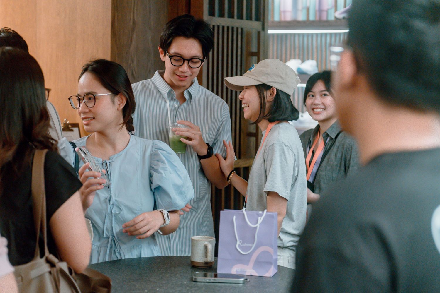 People interact in a casual office setting with glass walls and modern decor visible in the background.