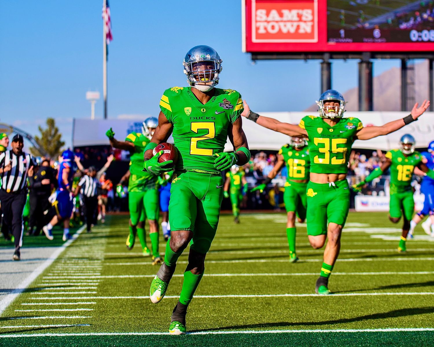 Oregon football players in bright green uniforms celebrate a touchdown after intercepting a pass during the Las Vegas Bowl.
