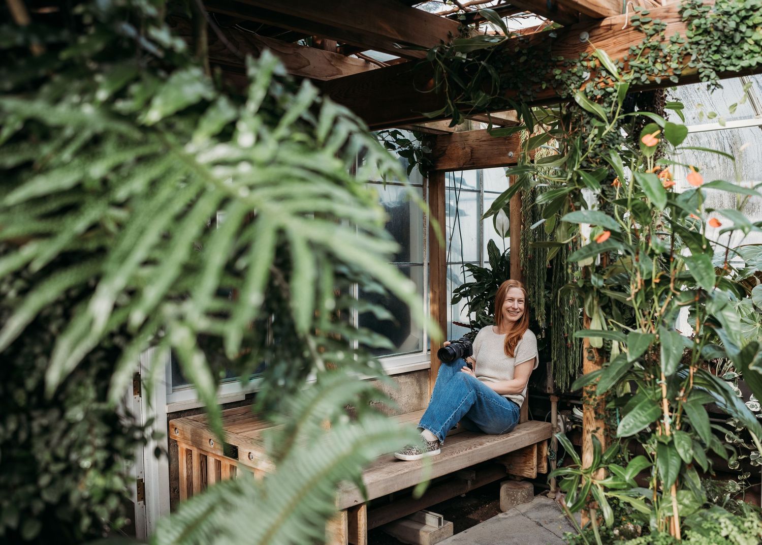 A lush greenhouse interior with wooden beams and tropical plants creating a serene botanical atmosphere.