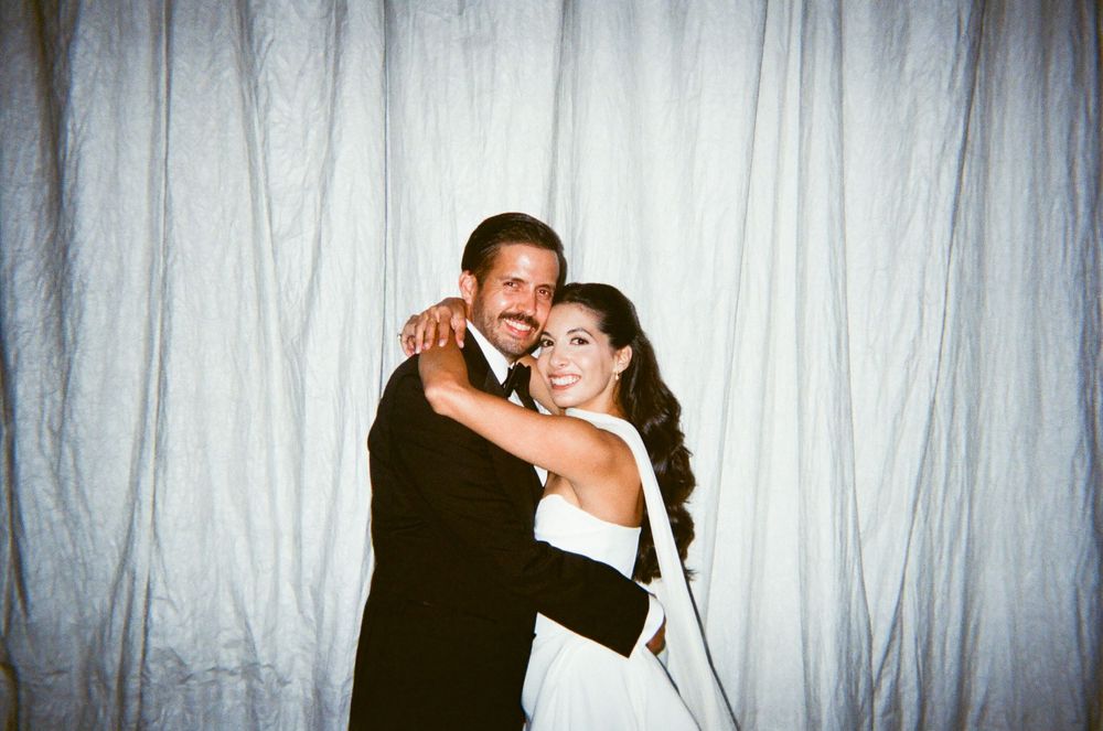 A couple dancing together in front of a white curtain backdrop, captured in a series of romantic poses.