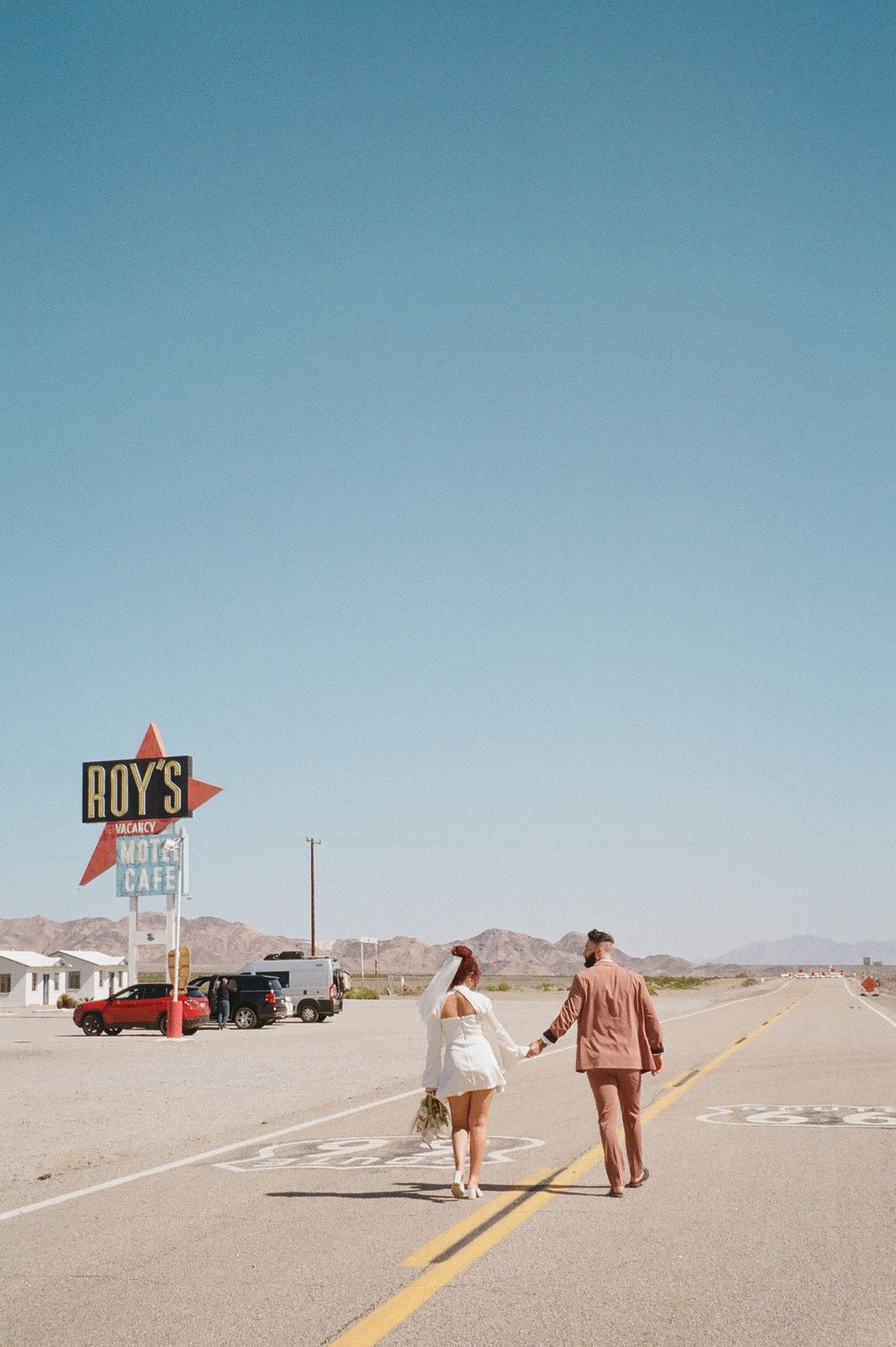 A sequence of desert highway scenes with a lone figure walking towards Roy's diner sign in the distance.