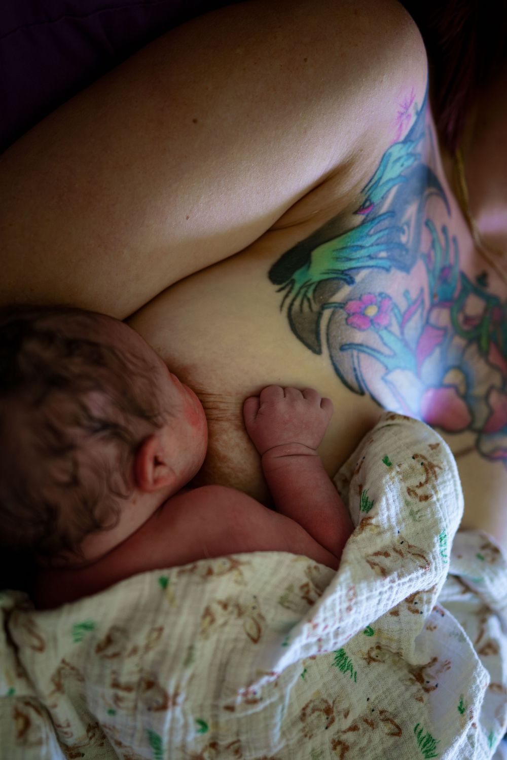 A close-up view of colorful floral tattoos visible on skin against white bedding.