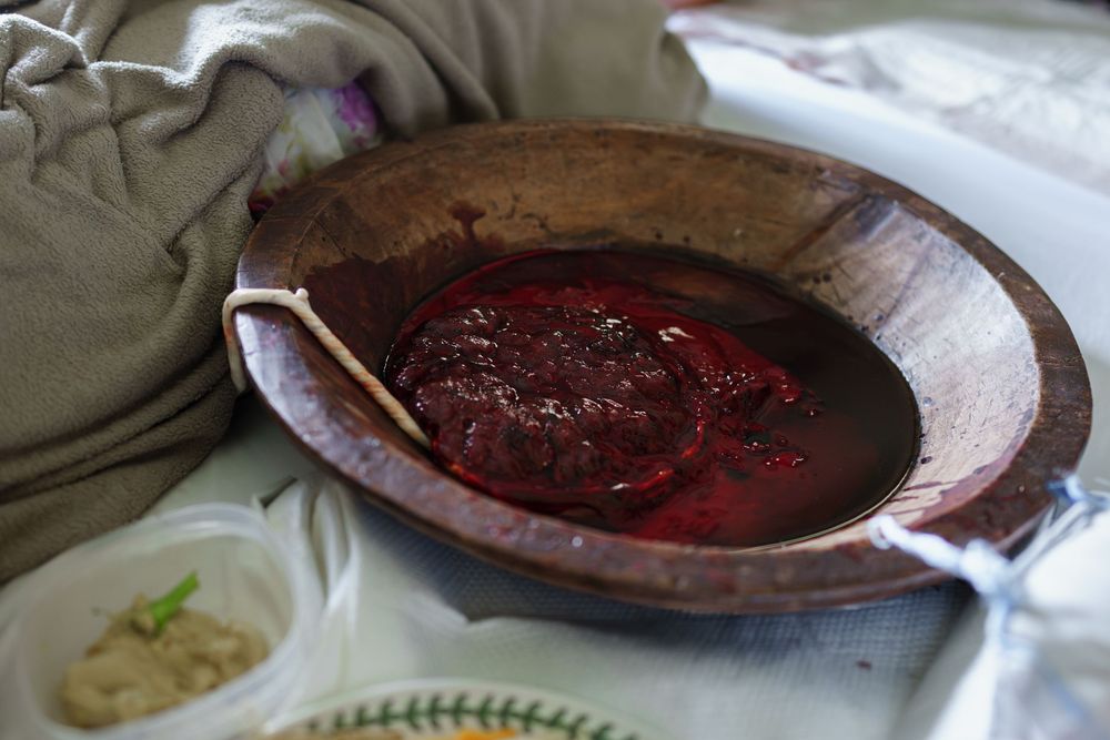 A dark reddish-brown sauce or mixture in a wooden bowl on white fabric.