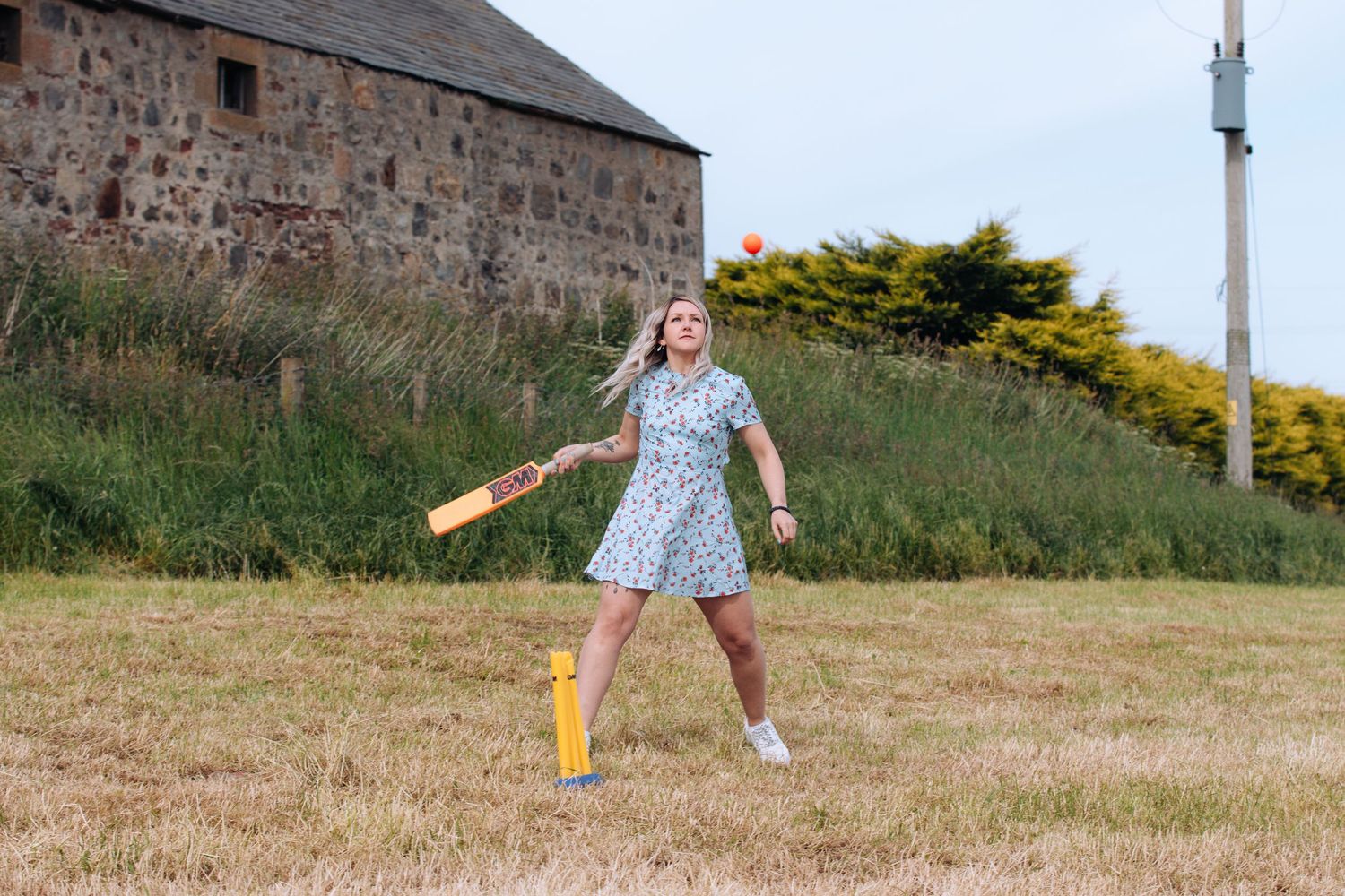 A sequence of photos showing someone in a floral dress dancing and twirling in a grassy field.