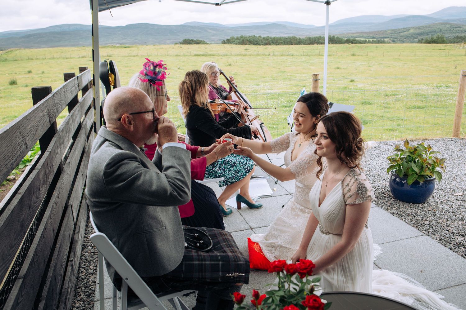 A couple shares an intimate moment during their wedding reception under a white tent with scenic mountain views.