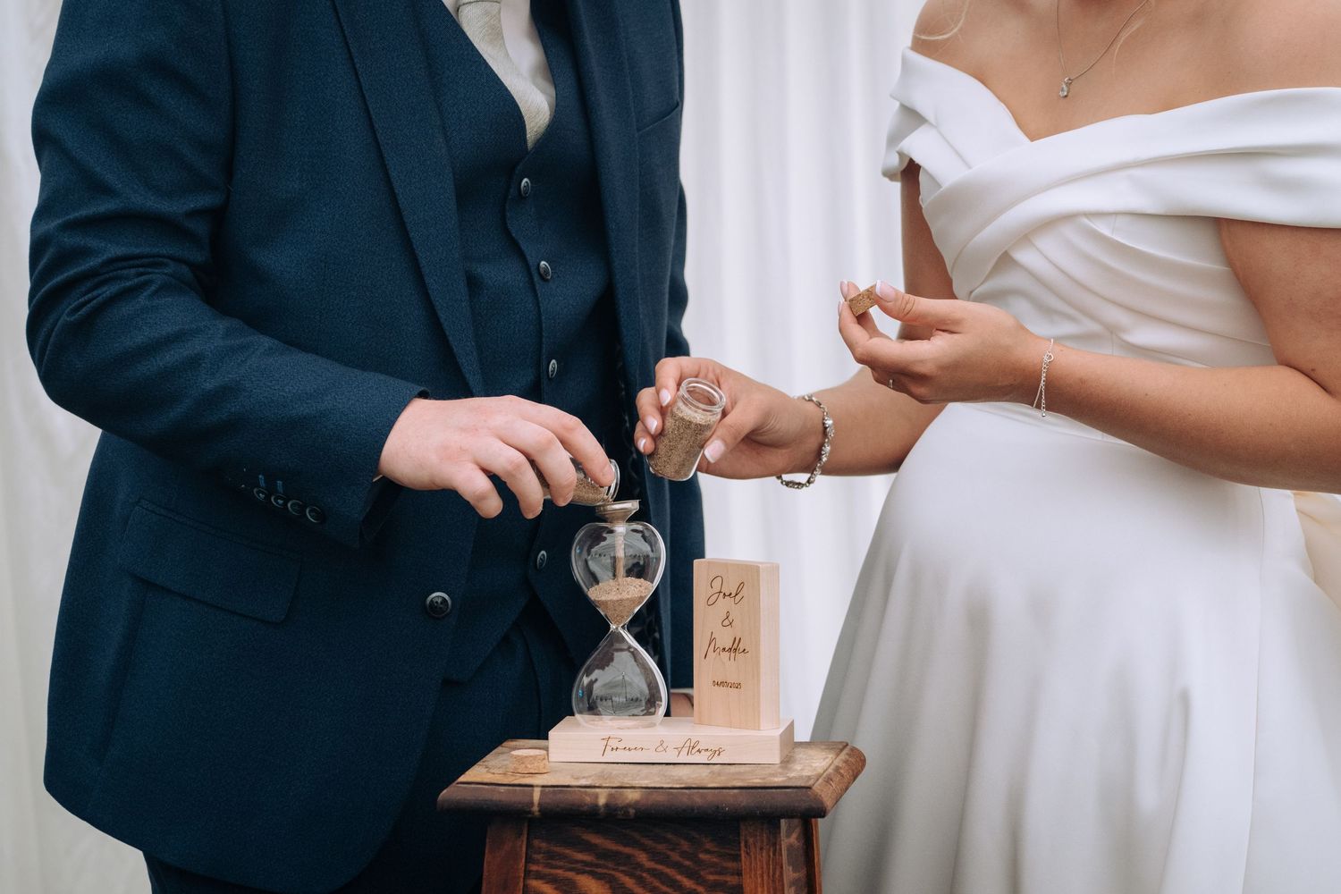 A wedding couple stands together while signing their marriage documents at an elegant indoor ceremony.