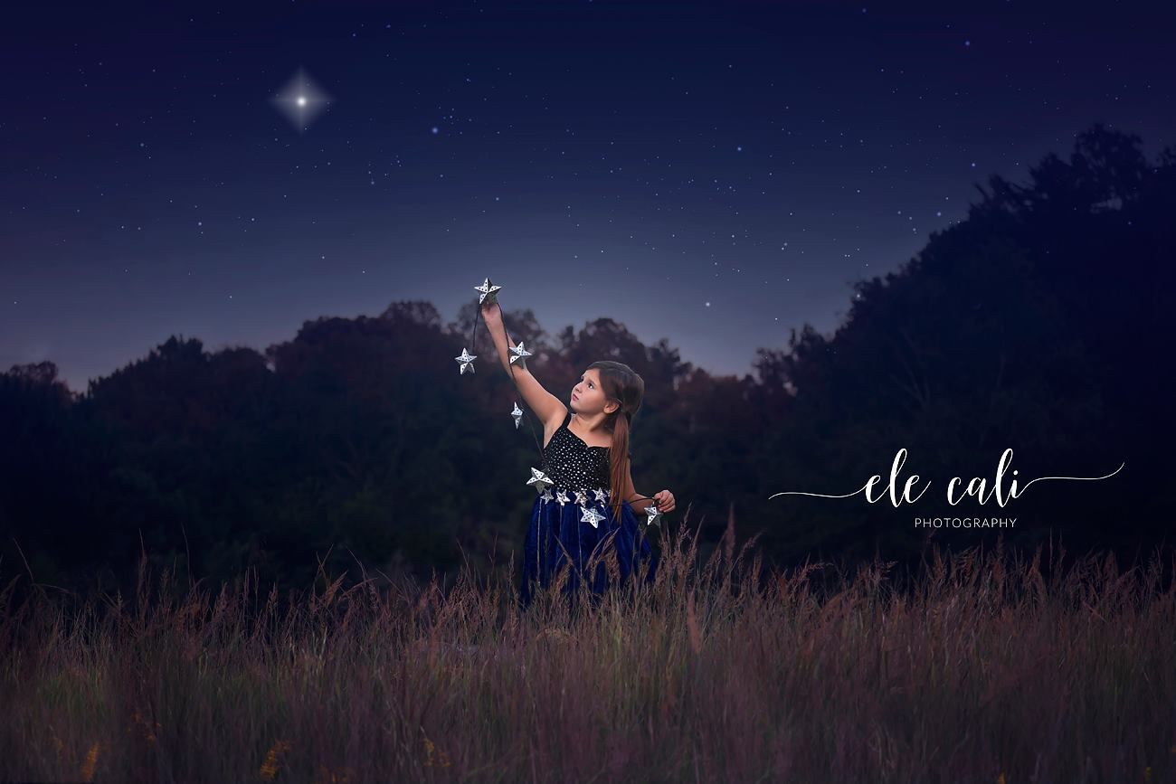Dreamy nighttime photography session in a field under starlit sky with dramatic lighting.