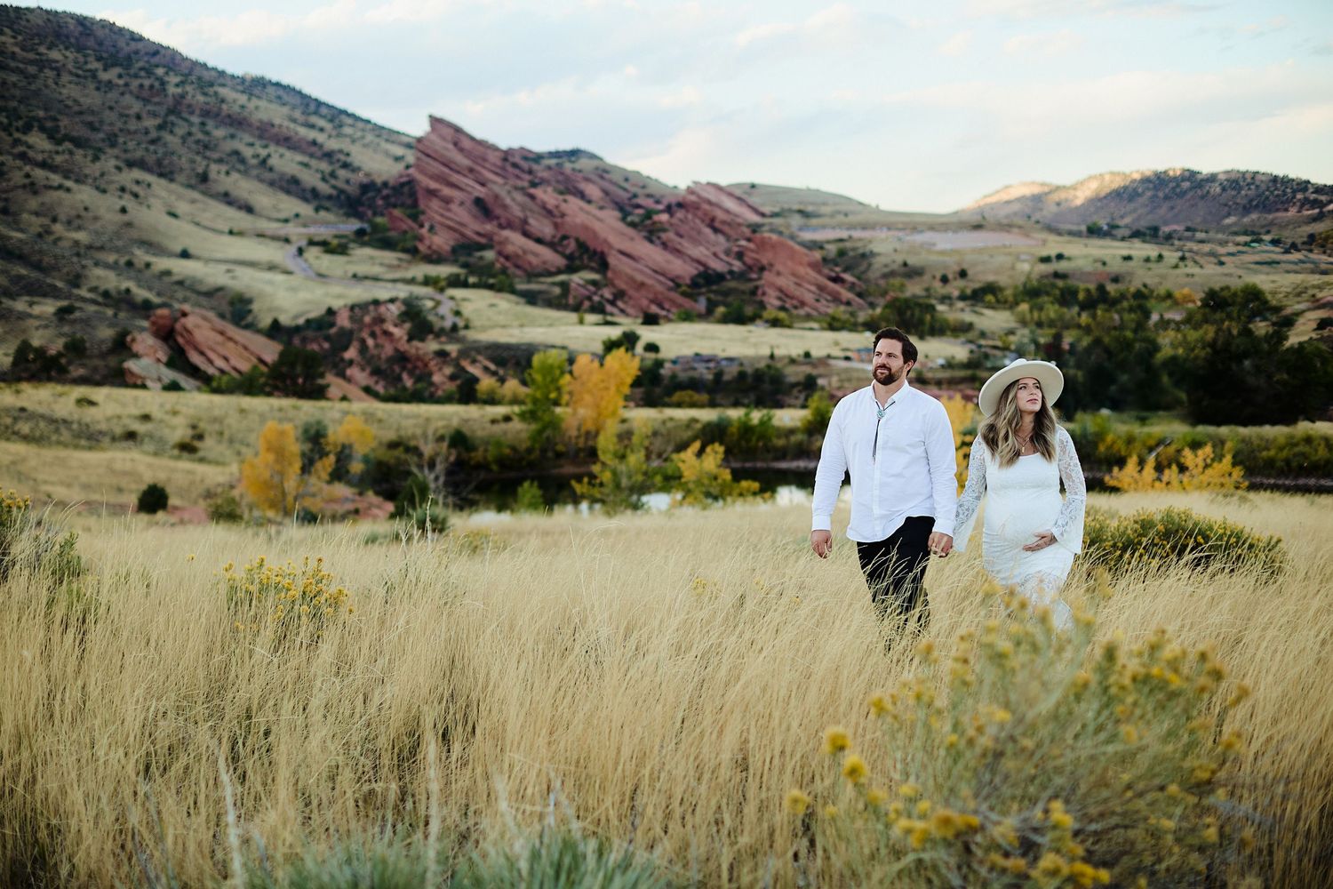 Couple holding hands during maternity photoshoot at Mt Falcon East with Colorado mountain views in background