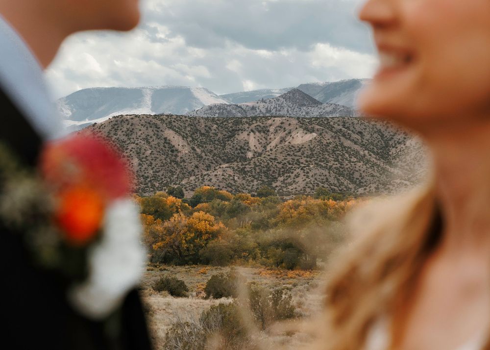 Mountain landscape framed between bride and groom with colorful autumn foliage in background.