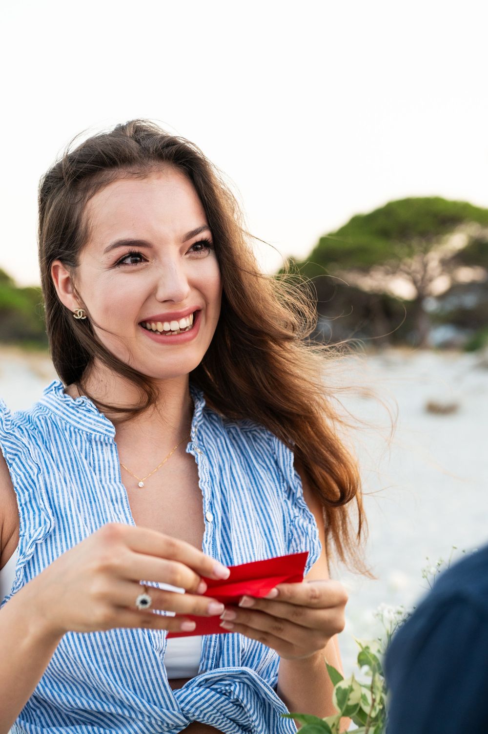 A couple shares a joyful moment on the beach as they look at something together in casual summer attire.