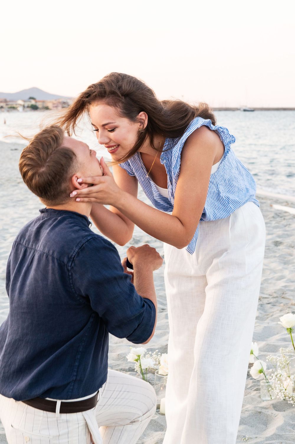 A couple sharing their first kiss after a beach proposal.