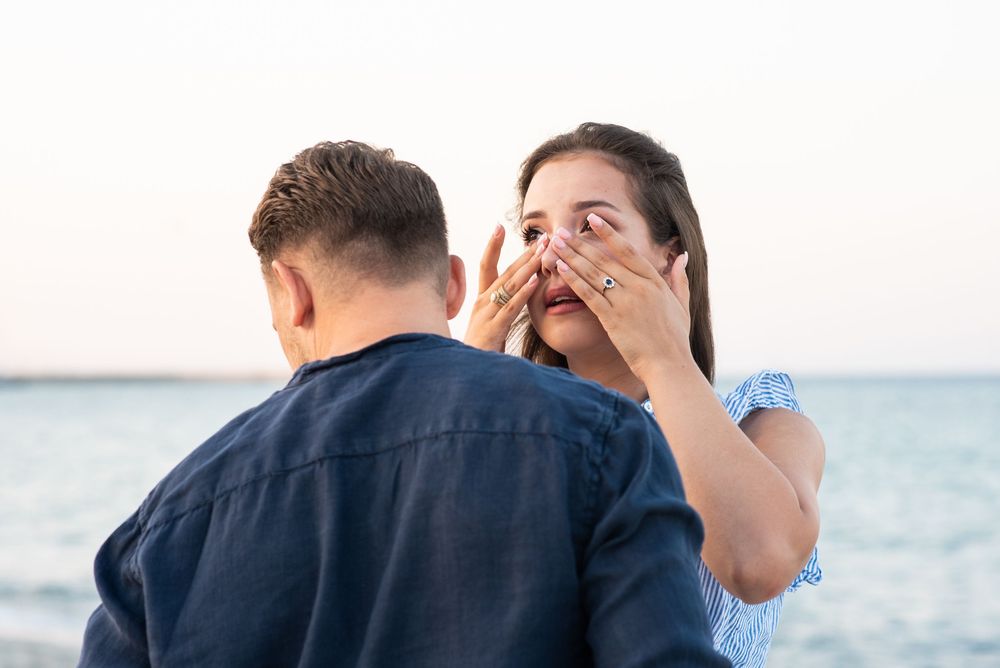 A romantic beach proposal captured in a series of emotional moments by the water.
