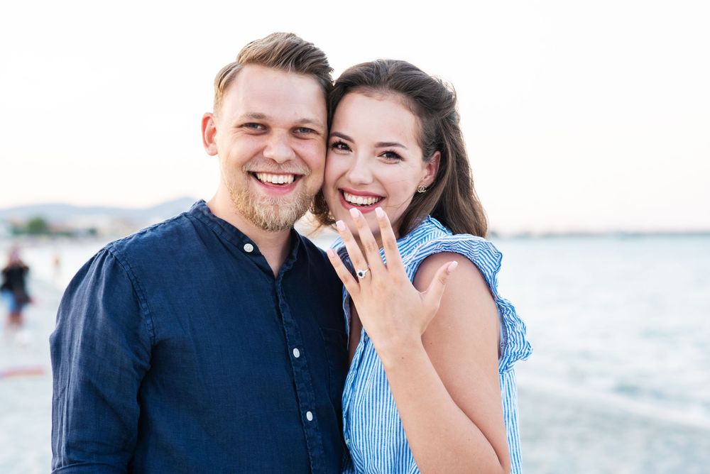 Happy couple shares emotional moment during beachside engagement.
