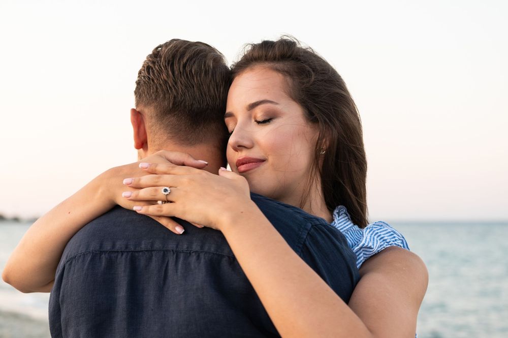 Romantic beach engagement photos with ocean backdrop at sunset.