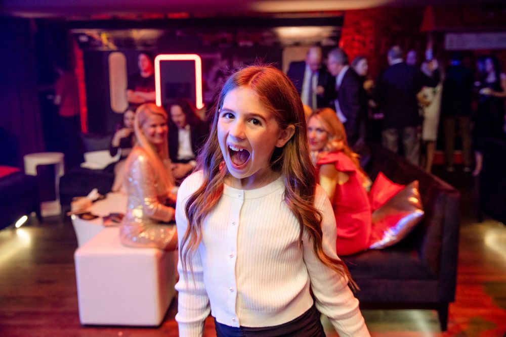 An enthusiastic woman in a white sweater enjoying herself at a lively nightclub event.