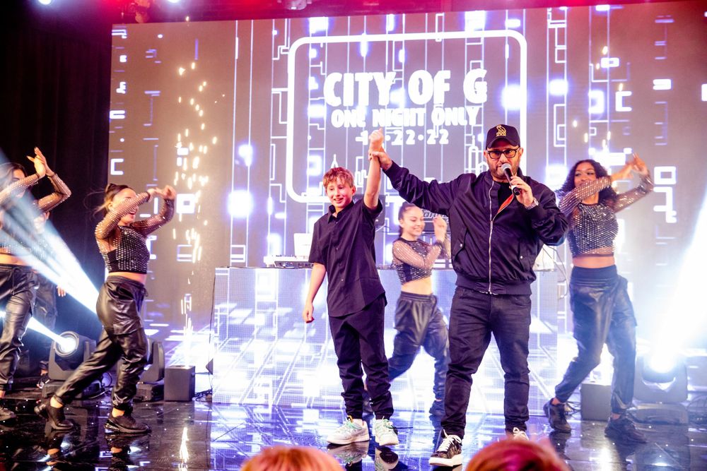 Performers on stage with digital backdrop and sparkling effects during live show.
