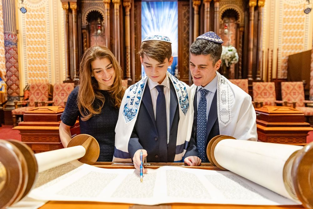 People gathered at a synagogue reading from prayer books during a religious ceremony.