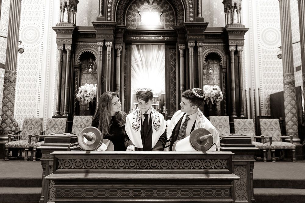 Black and white photo of congregants gathered around a Torah scroll at the synagogue altar.