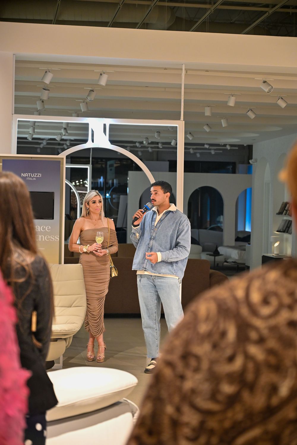 People gathered in a modern retail space with glass walls and track lighting for what appears to be a business event.