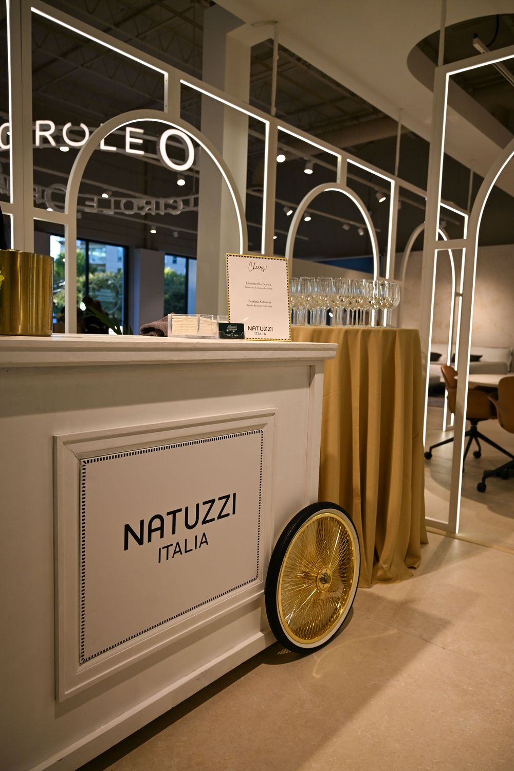 A modern showroom display featuring Natuzzi Italia branding with white panels and gold accents in a retail setting.