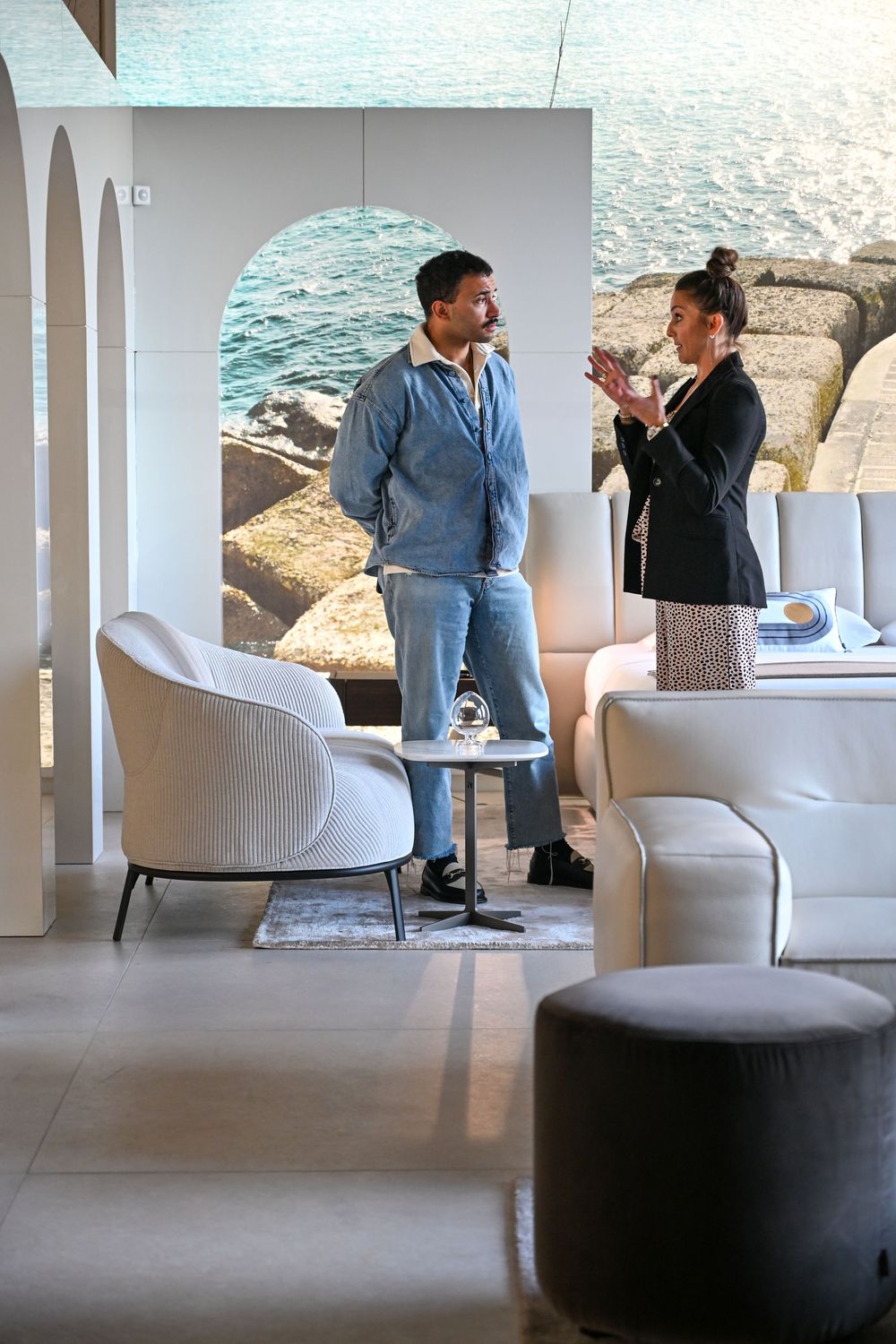 People sit in a modern white lounge area with sleek upholstered chairs and minimalist decor.