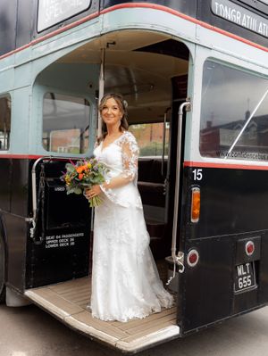 A vintage black London bus serves as a unique wedding transportation vehicle with white and orange accents.